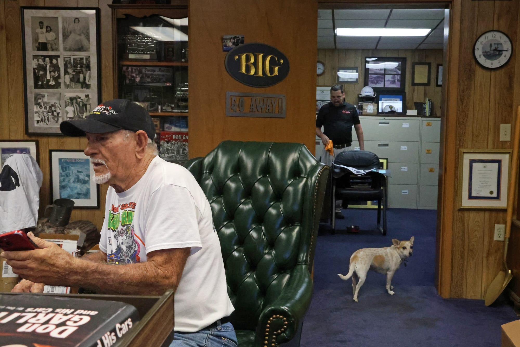 Garlits holds a phone while a little white and tan watch dog surveys the area on Monday, Sept. 15, 2025.