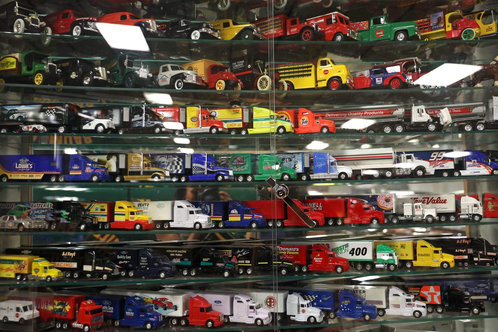 A wall of semi-trucks and farm trucks sit in a glass container in Garlits' musuem on Monday, Sept. 15, 2025.